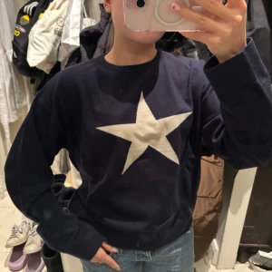Mörkblå tröja med stjärna från Gina Tricot - Säljer en mörkblå tröja från Gina Tricot med en stor vit stjärna på framsidan. Tröjan har en bekväm passform. Hör av dig vid frågor! 😊