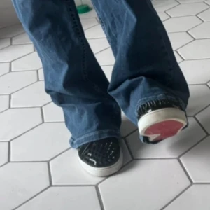 Svarta louboutin skor - Snygga svarta sneakers med nitar och vit sula. Skorna har en glansig finish och vita snören. Perfekta för att ge din outfit en edgy touch. Köpte i Milano sommaren 2024! Mycket bra skick, svårt att hitta dessa skor i detta skicket för bar 3800 