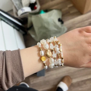 Pärlarmband med gulddetaljer - Charmigt set av armband med vita pärlor och guldfärgade detaljer. Armbanden har olika former av pärlor och små guldfärgade kulor, vilket ger en elegant och lekfull look. Perfekt för att lägga till en touch av stil till din outfit. Handgjorda, alla för 70kr eller 29kr/st  