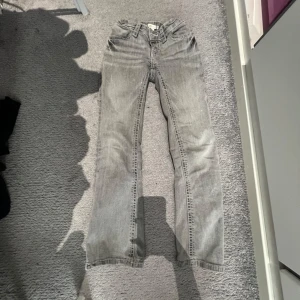 Grå jeans från Gina Tricot - Snygga grå jeans från Gina Tricot med en klassisk femficksdesign. De har en rak passform och är perfekta för en avslappnad stil. Jeansen har dekorativa sömmar på bakfickorna och en bekväm midja.