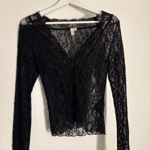 Svart spetsblus från Nelly - Säljer en elegant svart spetsblus från Nelly. Blusen har långa ärmar och en v-ringad design med knappar framtill. Perfekt för en stilfull look. Köpt för 400 kr på Nellys hemsida 💞