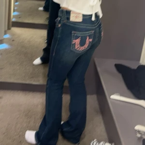True religon jeans - Snygga mörkblå jeans med broderade detaljer på bakfickorna i rosa. De har en bootcut-stil och låg midja, vilket ger en klassisk look. Perfekta för en avslappnad stil. Köpta på Nelly store i Stockholm. Inte så mycket använda, storlek W 25 motsvarar S typ. Jag är 167 cm och de är lite långa för mig. Slutsålda överallt