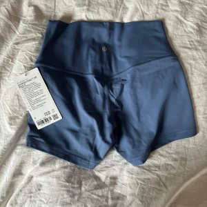 Blå shorts från Lululemon - Snygga blå shorts från Lululemon med hög midja och en bekväm passform. Perfekta för träning eller en aktiv dag. Materialet är mjukt och stretchigt för maximal rörelsefrihet. Aldrig använda