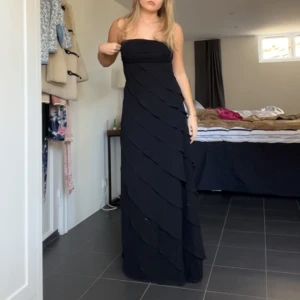 Perfekta balklänningen - Elegant svart axelbandslös långklänning med volangdetaljer. Den perfekta balklänningen!!!🙌🏻💃🏼 Säljer då den tyvärr är förliten för mig💔💔