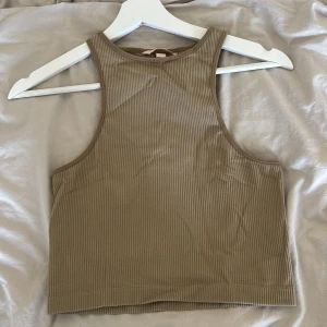 Beige ribbad linnetopp - Säljer en stilren beige ribbad linnetopp från H&M. Toppen är ärmlös och har en tight passform som passar perfekt för varma dagar. Den är gjord i ett mjukt och stretchigt material för extra komfort.