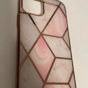 Rosa och vit mobilskal med geometriskt mönster för iPhone 12 mini - Snyggt mobilskal med ett geometriskt mönster i rosa och vitt. Skalet har en marmorerad effekt och ger ett stilrent intryck. Perfekt för att skydda din mobil med stil. För iPhone 12 mini
