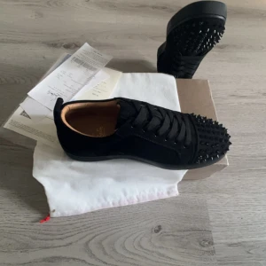Svarta sneakers med nitar - Snygga svarta sneakers från Christian Louboutin med nitar på ovansidan och den ikoniska röda sulan. Skorna har snörning och en stilren design som sticker ut medkommer dustbag och kvittot! Hojta till vid funderingar!! Obs har fler!