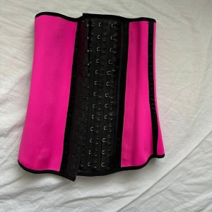 Rosa waist trainer/korsett - Snygg rosa waist trainer med svarta detaljer och justerbar passform. Perfekt för att forma midjan och ge stöd. Tillverkad i ett stretchigt material som ger en bekväm känsla. Säljer då den tyvärr inte passade mig. Pris kan diskuteras vid snabb affär