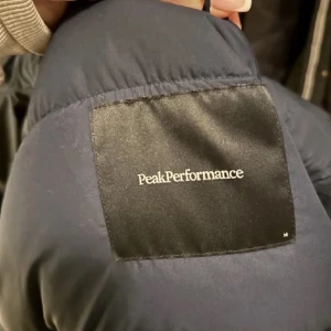 Mörkblå dunjacka från Peak Performance - Säljer en snygg och varm mörkblå dunjacka från Peak Performance. Jackan har en praktisk dragkedja och en mysig huva för extra skydd mot kylan. Perfekt för vintern och hösten! Skicka om du vill ha mer bilder på denna. Säljer eftersom jag fick köpt fel (herr) istället för dam. Det är ungefär denna jacka förutom att skillnaden fickorna. Original pris 4200. 
