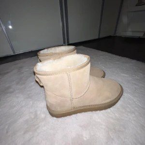 Beige uggs med foder - Säljer ett par mysiga beige boots med mjukt foder. Perfekta för kalla dagar med sin varma insida. De har en enkel design och är lätta att matcha med olika outfits. Jag vet inte riktigt vart den är ifrån dock är det ej uggs, säljer pågrund av att dem aldrig kommer till användning, står i skon att det är läder!🤍pris kan diskuteras!