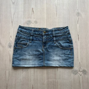 Ljusblå lågmidjad jeanskjol  - Blå lågmidjad jeanskjol från Sublevel i fint skick. Står storlek M men jag skulle säga att den passar mer som S. Tvärs över midjan är det 38 cm + stretch och den är ca 31 cm lång (längs med sidan). Använd gärna köp nu!