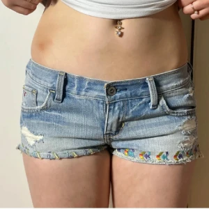 Lågmidjade jeansshorts med hål hollister vintage 2000s minishorts - Står ingen storlek men passar mig som brukar ha W27. Shortsen har resår bak som ”töjs” när de bärs. Midjemått när resåren är utsträckt:36-38cm. Köp sker via köp nu, jag postar inom 24h. Kvar tills markerad såld 
