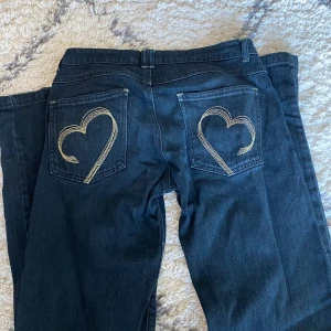 Vintage Miss Sixty jeans  - Säljer ett par svarta lågmidjade  jeans från Miss Sixty med snygga guldiga hjärtan broderade på bakfickorna. Kostar original ca 2000kr men säljs inte längre. 