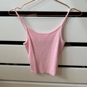 Ljusrosa ribbad linnetopp FB Sister - Supersöt ljusrosa ribbad linnetopp från FB Sister i storlek XXS. Toppen har smala axelband och ärmlös design, perfekt för varma dagar. Mjuk och stretchig känsla som sitter snyggt och bekvämt. Enkel att matcha med jeans eller kjol för en chill look.