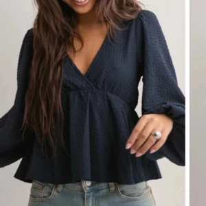 Nelly tröja - Säljer en mörkblå blus med omlott och v-ringning. Blusen har långärmade, lite puffiga ärmar och ett lätt strukturerat tyg som ger en snygg känsla. Använt några gånger men jättefin skick 💕