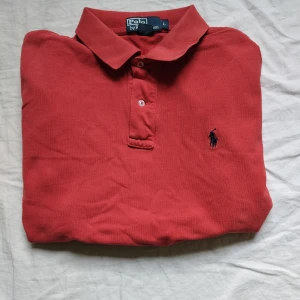 Ralph Lauren piké  - Tjo gubbar! En ny fet röd Ralph Lauren piké med märket i rött. Väldigt väldigt bra skick. Storlek L. Passar alla. Kolla gärna profilen där de nu kommit in en fet leverans me Ralph Lauren kläder. Ha de gött!!