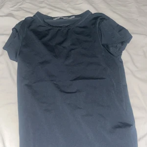 Mörkblå t-shirt från 157, XS - En basic mörkblå t-shirt från 157 i storlek XS. T-shirten har rund halsringning och korta ärmar, perfekt för en clean och enkel stil. Tillverkad i mjuk bomull som känns skön mot huden. Passar dig som gillar minimalistiska plagg.