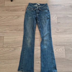 Blå bootcut jeans från Gina Tricot - Snygga blå bootcut jeans från Gina Tricot, modell Perfect Jeans. Jeansen har dragkedja och knapp framtill samt detaljerade bakfickor. Perfekta för en avslappnad och trendig look.