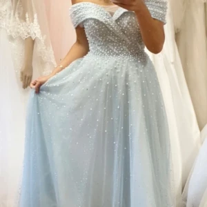 Ljusblå långklänning med pärlor - Magisk ljusblå långklänning med offshoulder och snörning i ryggen. Klänningen är täckt av pärlor och glittriga detaljer, har en vacker v-ringning och ett svepande tyll-liknande tyg. Perfekt för bal eller student. Ger riktiga prinsessvibbar! Endast buren en gång. Pågrund av snörningen i ryggen så passar den storlek M, S, XS!