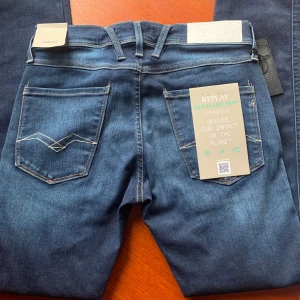 Replay Anbass Hyperflex jeans blå - Snygga blå Replay Anbass Hyperflex jeans med slim fit och klassisk femficksdesign. Jeansen är tillverkade i återvunnet material och är i storlek w29 l32 helt nya och taggarna kvar prislapp är kvar och påse finns för bevis. Ordinarie pris är 1800