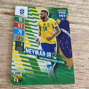 Neymar Jr International Star - Samlarbok/kort om fotbollsstjärnan Neymar Jr från Panini FIFA 365-serien. Perfekt för dig som älskar fotboll, samlar på sportkort eller vill ha något unikt om en av världens största spelare. Färgstark design och coola stats – ett måste för unga sportfans!