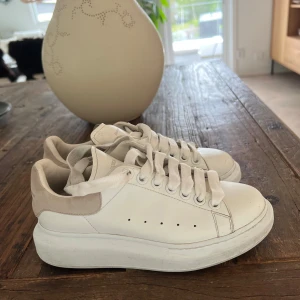 Alexander McQueen vita sneakers - Vita sneakers från Alexander McQueen med rosa/beige detalj. Något slitna, därav priset. 