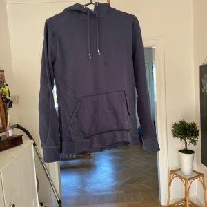 Hoodie - En enkel och stilren mörkblå hoodie från 157 i storlek S. Tröjan har huva med snörning, stor magficka framtill och långa ärmar. Perfekt för chill dagar eller när du vill ha något bekvämt och snyggt på dig.