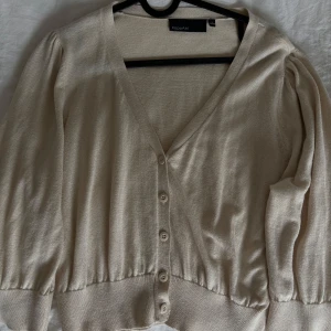 Beige kofta med v-ringning KappAhl - Beige kofta från KappAhl med v-ringning och knappar framtill. Koftan är lite kortare och passar mig som brukar ha S!💖💖