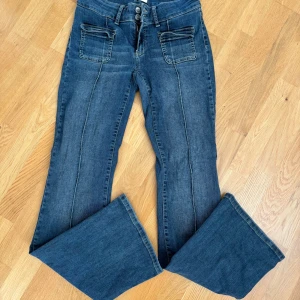Blå bootcut jeans från Nelly - Snygga low/mid rise jeans med coola fickor framtill och en sydd detalj som går längs benet ner och även dubbelknäppning, små i storleken, skriv vid frågor💘