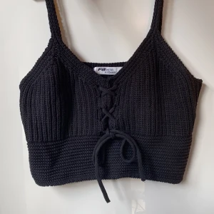 Svart stickat linne -  Svart stickad topp från FB Sister med smala axelband och snörning framtill. Toppen är croppad och har ribbad struktur upptill och bredare stickning nedtill. Meddela gärna för mått eller andra frågor☺️