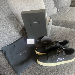 Svarta Saint Laurent sneakers - Säljer ett par svarta sneakers i lyxig och stilren design – inspirerade av Saint Laurent. Storlek 43, helt nya och oanvända.  Mjukt läder, rätt form och tyngd, med fina detaljer. Perfekta för dig som gillar clean look med klass.  Levereras med låda, dust bag och extra skosnören.  Skriv vid intresse – kan skicka fler bilder eller info i DM! 