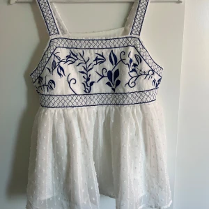 Vit topp med blåa broderier  - Vit sommar topp med blåa broderier i storlek xs. Köpte secondhand men kommer ursprungligen från shein. Säljer då jag gör en stor garderobs rensning och denna tyvärr inte kommit till så mycket användning för mig 🩷