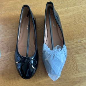 Svarta ballerinaskor med rosett - Aldrig använda ballerina skor, dem ligger fortfarande kvar i förpackningen. Storlek 39 