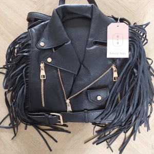 Svart ryggsäck med fransar från Beauty Bags, Spanien - Helt ny och oanvänd cool svart ryggsäck i skinnimitation med fransar på sidorna och detaljer i guld. Designen är inspirerad av en bikerjacka med dragkedjor, knappar och bälte framtill. Perfekt för dig som vill sticka ut med en edgy och unik väska. Hör av dig vid frågor eller prisförslag!!😊 Nypris 350 kr så säljer för 300 kr🌸
