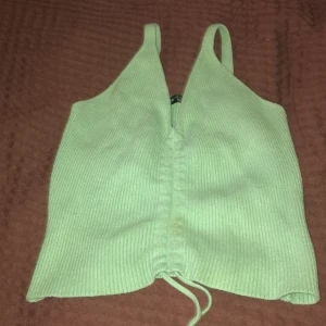 Ljusgrön ribbad linnetopp från SHEIN - Snygg ljusgrön linnetopp från SHEIN med ribbad struktur och smala axelband. Toppen har en v-ringad front och snörning längst ner för att justera passformen. Perfekt för att ge din outfit en fräsch vibe i sommar.