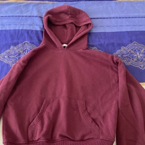 Vinröd hoodie från 157, storlek S - Mysig vinröd hoodie från 157 med klassisk huva och stor magficka. Tröjan har ribbade muddar och är tillverkad i mjuk bomull, perfekt för chill dagar. Enkel och stilren design utan mönster eller tryck, passar dig som gillar basic och comfy vibes.