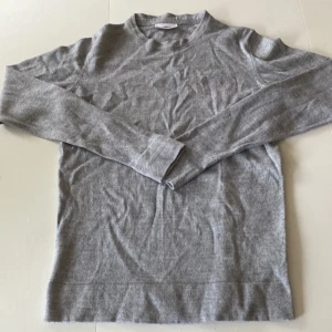 Grå stickad tröja från Lindbergh - Säljer en stilren grå stickad tröja från Lindbergh White. Tröjan har rund hals och långa ärmar, perfekt för dig som gillar enkel och clean look. Materialet är mjukt och skönt mot huden, passar till jeans eller chinos. En klassiker i garderoben!