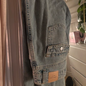 Perfect Jeans ljusblå  - Säljer ett par ljusblå jeans från Gina Tricot ”Perfect Jeans” med fickor med knapp baktill. Jeansen har lite av en baggy vibe och klassisk jeansknapp.