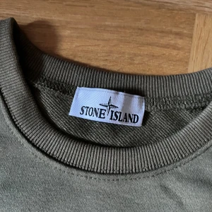 Stone Island olivgrön sweatshirt - olivgrön sweatshirt från Stone Island med rund hals. Tröjan har den Stone Island-patchen på vänster ärm, både den svarta och den gula patchen kommer med! Har knappt använt den då jag har bytt stil. OBS: Pris kan diskuteras