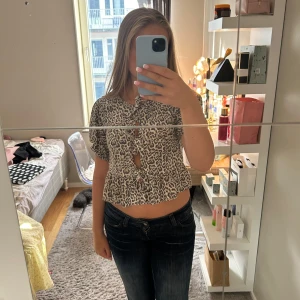 Leopardmönstrad croppad blus med knyt - Säljer en croppad blus med leopardmönster i beige och svart. Toppen har korta puffärmar, knyt framtill och volang vid nederkanten. Från strandinavius. Köpt för 300 säljer för 220 men priset går att diskutera. Skriv till mig vid frågor🫶