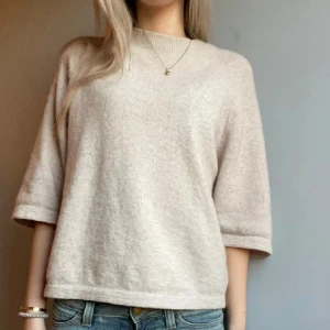 Beige stickad tröja & Other Stories - Supermysig beige stickad tröja från & Other Stories med rund hals och trekvartsärm. Tröjan har en loose passform och är tillverkad i mjukt material som känns lyxigt mot huden. Perfekt att styla med jeans eller kjol för en chill look.