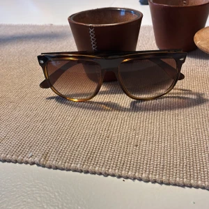 Ray-Ban boyfriend solglasögon - Säljer ett par klassiska Ray-Ban boyfriend solglasögon med brunmelerad båge och svarta detaljer. Glasen är tonade i brunt och bågen har en snygg, fyrkantig form. Medföljer original svart fodral i skinnimitation. Perfekt för dig som gillar tidlös stil. Använda typ 2 gånger och i superbra skick. Nypris ca 1200 kr. Frågor och funderingar hör av er!