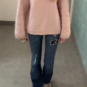 Blå bootcut jeans - Säljer ett par blå lågmidjade bootcut jeans från Cult of Individuality. Jeansen har slitna detaljer och coola svarta lappar med nitar på framsidan. Köpte för 950 Midjemått:37 Innerbenslängd:83