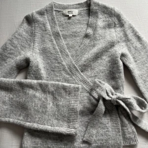 Grå omlottkofta från Gina Tricot - Mysig, populär grå omlottkofta från Gina Tricot med utsvängda ärmar. Använd två gånger så i nyskick! Storlek XS💕