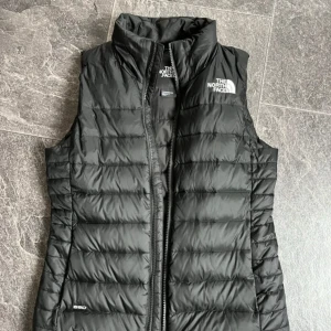 Svart dunväst från The North Face - Säljer nu min svarta dunväst från The North Face med logga på bröstet. Den är använd fåtal gånger så är i mycket fint skick!✨ Västen kostade 1370kr ny från ASOS. Bara att fråga vid frågor eller lägg ett bud🔥