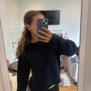 Mörkblå stickad tröja med paljetter - Mörkblå stickad tröja med glittriga paljetter och öppen rygg med snygg detaljband. Tröjan har lång ärm och loose passform, perfekt för dig som gillar att sticka ut lite extra. Mjuk och skön, passar till svarta jeans eller kjol. Storlek 158/164 men sitter som en s på mig som vanligtvis brukar ha xs och är 164cm lång 