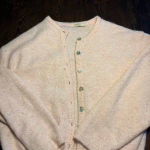 Ljusrosa kofta från Gina Tricot - Supermysig ljusrosa kofta från Gina Tricot med rund hals och glansiga knappar framtill. Koftan är stickad och har långa ärmar, perfekt för att ge din outfit en soft vibe. Passar dig som gillar enkel och clean stil med en touch av pastell.