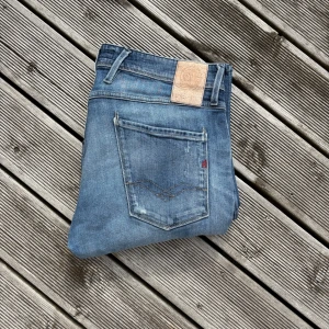 Replay Anbass ljusblå jeans straight fit - Säljer ett par Replay Anbass jeans i ljusblå tvätt med klassisk femficksdesign och snygga slitningar. Jeansen har rak passform, normal midja och detaljerad bakficka med Replay-logga. Perfekt för dig som gillar stilrena och bekväma jeans. Kom gärna med frågor!🙌 W33 L32