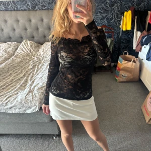 Offshoulder spetstopp - Säljer en svart långärmad topp i transparent spets med blommigt mönster. Modellen är offshoulder och sitter tight mot kroppen, perfekt för att ge en edgy vibe. Spetsen är detaljerad och ger en cool look som sticker ut. Jättebra på fester och man kan även ha linne under. Vet tyvärr inte vart jag köpt den eller exakt storlek, men skulle gissa på xs-s 