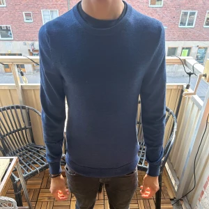 Blå merinoulltröja från C - Säljer en stilren mörkblå tröja från C i 100% merinoull. Tröjan har rund hals, lång ärm och en clean look utan mönster eller detaljer. Perfekt för dig som gillar enkel och snygg stil. Passar dig som vill ha en normal passform och mjukt material.